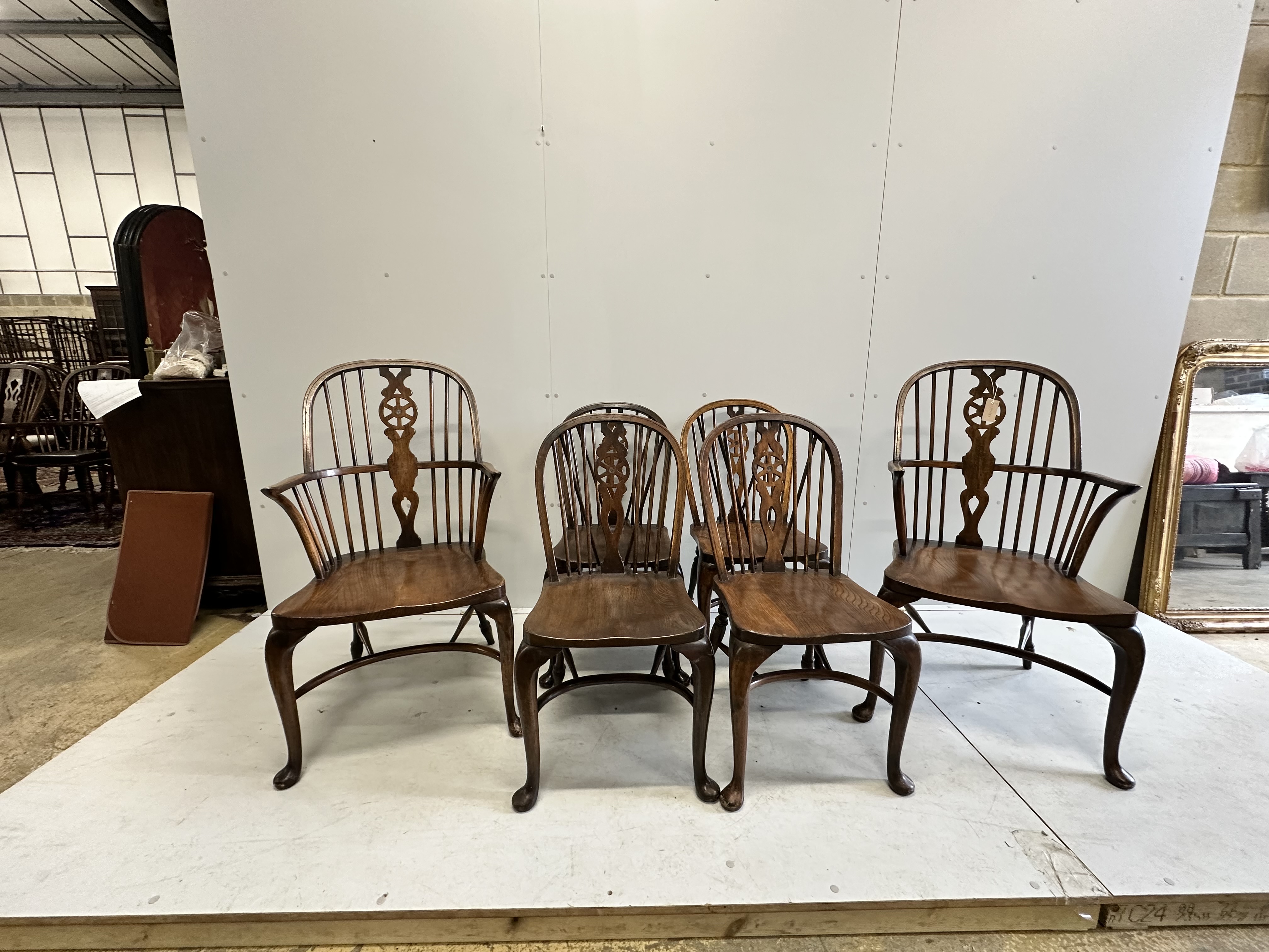 A set of six reproduction elm and beech Windsor wheel back dining chairs on cabriole legs with crinoline stretchers, two with arms